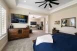 Experience luxury and comfort in this beautifully appointed bedroom, featuring a large wall-mounted TV, a rustic wooden dresser, and a plush navy blue bed with a cozy white throw.