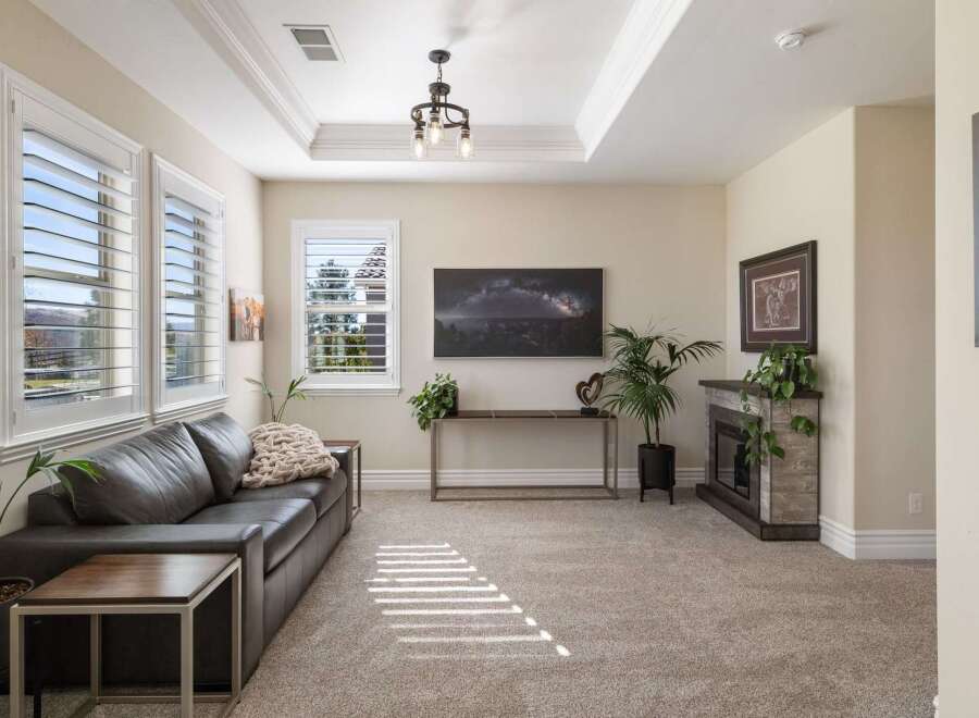Step into this inviting living room, featuring a plush dark leather sofa complemented by a cozy knit throw and modern side tables.