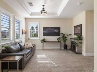 Step into this inviting living room, featuring a plush dark leather sofa complemented by a cozy knit throw and modern side tables.