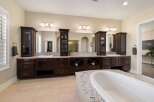 Indulge in luxury with this stunning master bathroom, featuring a spacious double vanity with dark wood cabinetry and granite countertops.