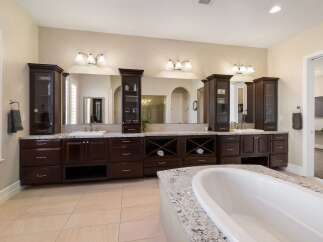 Indulge in luxury with this stunning master bathroom, featuring a spacious double vanity with dark wood cabinetry and granite countertops.