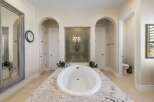 Indulge in luxury in this stunning master bathroom, featuring a freestanding soaking tub set atop a granite vanity.