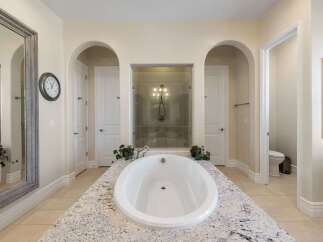 Indulge in luxury in this stunning master bathroom, featuring a freestanding soaking tub set atop a granite vanity.