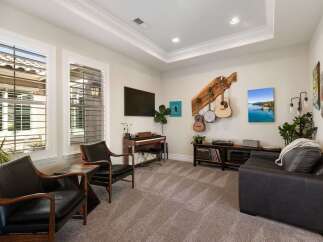 This inviting living room features a stylish entertainment setup with a piano, a television, and a collection of musical instruments displayed on the wall.