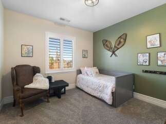 This charming bedroom features a cozy gray daybed adorned with a whimsical rainbow-themed comforter and pillows.