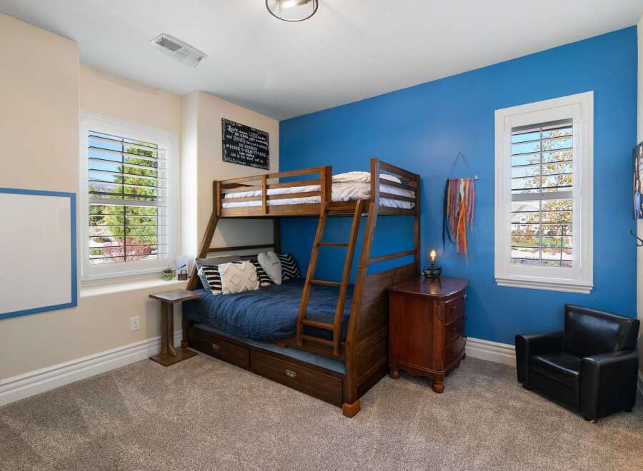 This charming bedroom features a space-saving wooden bunk bed with a pull-out trundle, perfect for accommodating guests or siblings.