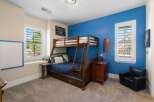 This charming bedroom features a space-saving wooden bunk bed with a pull-out trundle, perfect for accommodating guests or siblings.