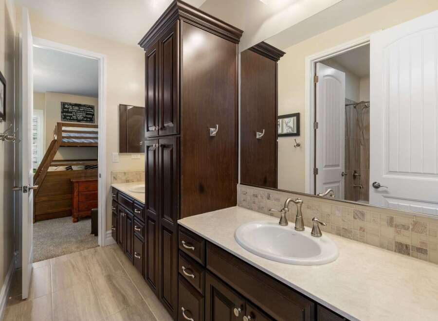 This spacious bathroom features a double vanity with dark wood cabinetry and a light-colored countertop, complemented by a tiled backsplash.