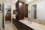 This spacious bathroom features a double vanity with dark wood cabinetry and a light-colored countertop, complemented by a tiled backsplash.