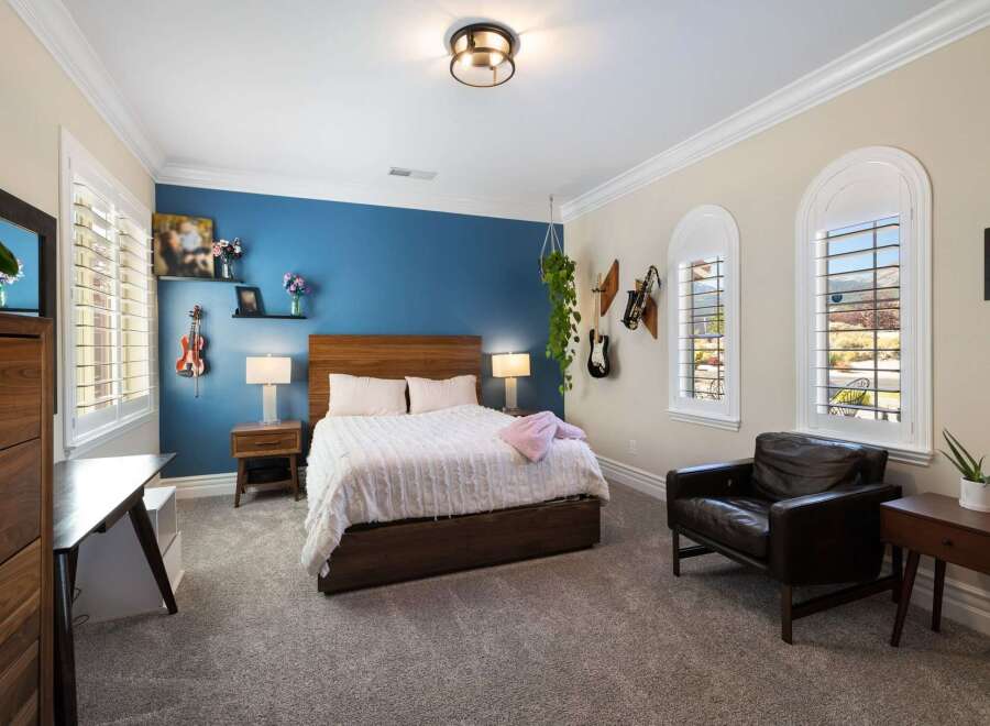 This inviting bedroom features a comfortable queen-size bed with a plush white duvet, complemented by a rich wooden headboard.