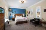 This inviting bedroom features a comfortable queen-size bed with a plush white duvet, complemented by a rich wooden headboard.