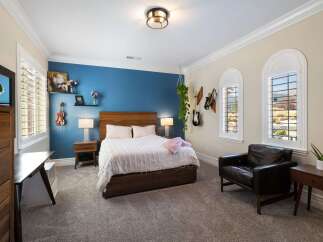 This inviting bedroom features a comfortable queen-size bed with a plush white duvet, complemented by a rich wooden headboard.