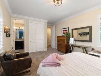 This inviting bedroom features a plush pink throw blanket draped over a white comforter, creating a cozy atmosphere.
