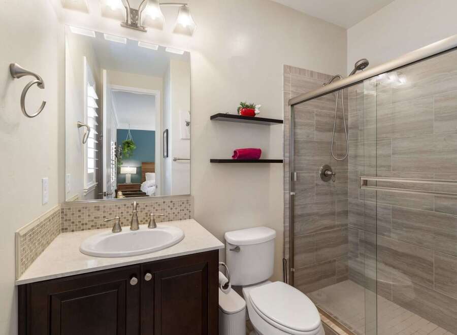 This modern bathroom features a sleek vanity with a white undermount sink and a tiled backsplash.