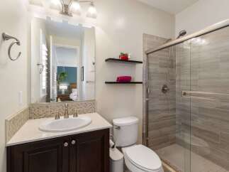 This modern bathroom features a sleek vanity with a white undermount sink and a tiled backsplash.