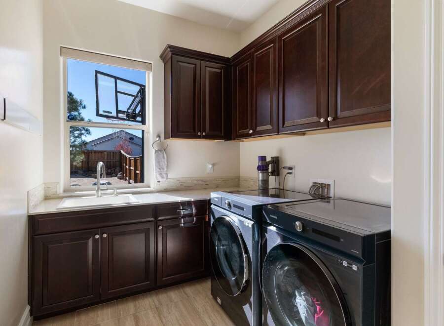 This spacious laundry room features dark wood cabinetry, providing ample storage above and below the countertop.