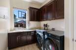This spacious laundry room features dark wood cabinetry, providing ample storage above and below the countertop.