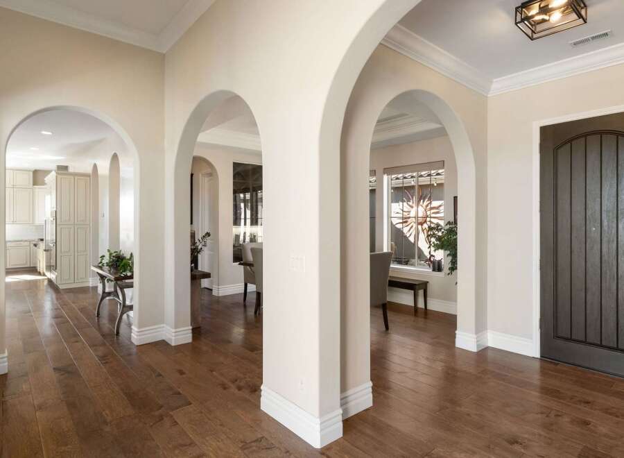 Step into a grand entryway featuring elegant arched doorways and rich hardwood flooring.