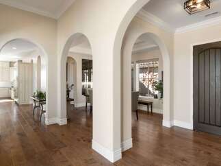 Step into a grand entryway featuring elegant arched doorways and rich hardwood flooring.
