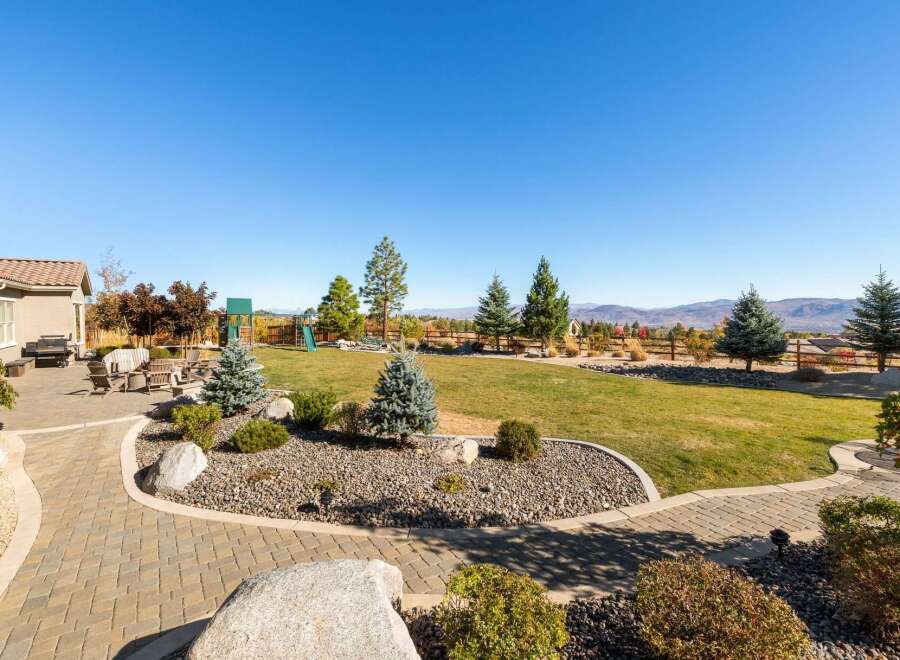 Enjoy outdoor living in this spacious backyard featuring a paved patio with comfortable seating and a built-in grill, perfect for entertaining.