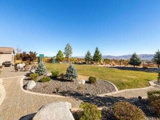 Enjoy outdoor living in this spacious backyard featuring a paved patio with comfortable seating and a built-in grill, perfect for entertaining.