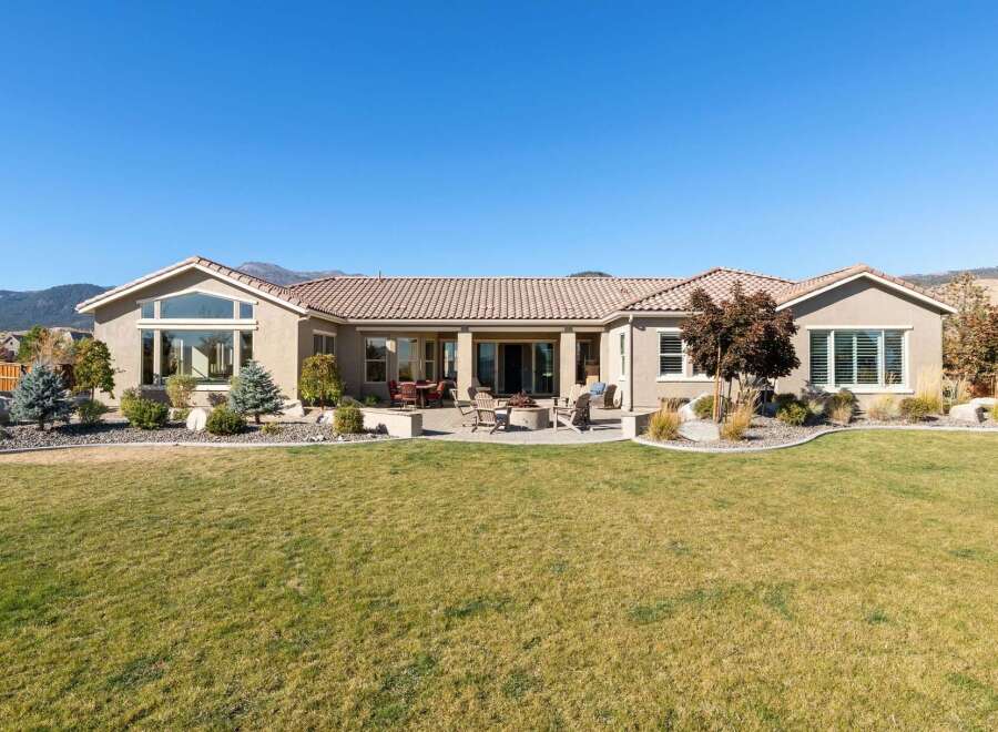 This stunning single-story home boasts a spacious backyard perfect for entertaining, featuring a paved patio with a fire pit and ample seating.