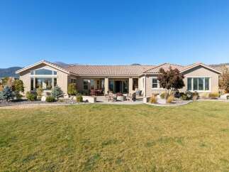 This stunning single-story home boasts a spacious backyard perfect for entertaining, featuring a paved patio with a fire pit and ample seating.