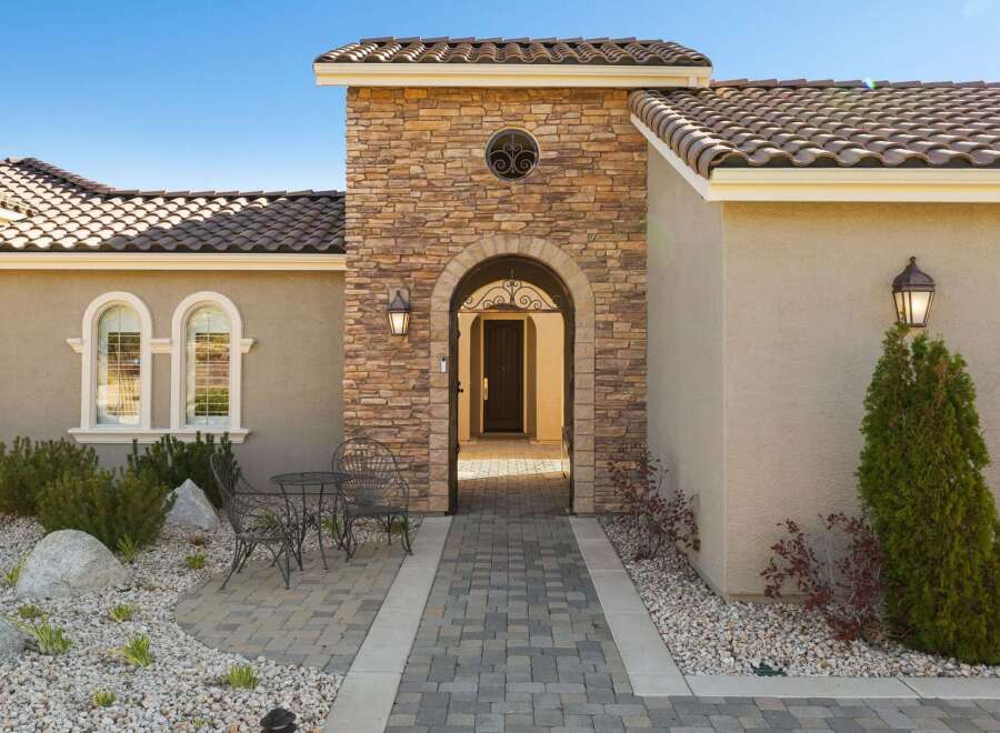 Step into luxury with this stunning home featuring a grand arched entryway adorned with natural stone.
