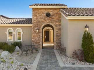 Step into luxury with this stunning home featuring a grand arched entryway adorned with natural stone.