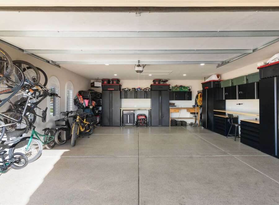 This spacious garage offers ample storage solutions with multiple black cabinets and shelving units, perfect for organizing tools and equipment.