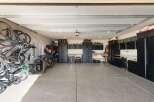 This spacious garage offers ample storage solutions with multiple black cabinets and shelving units, perfect for organizing tools and equipment.