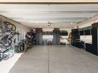 This spacious garage offers ample storage solutions with multiple black cabinets and shelving units, perfect for organizing tools and equipment.