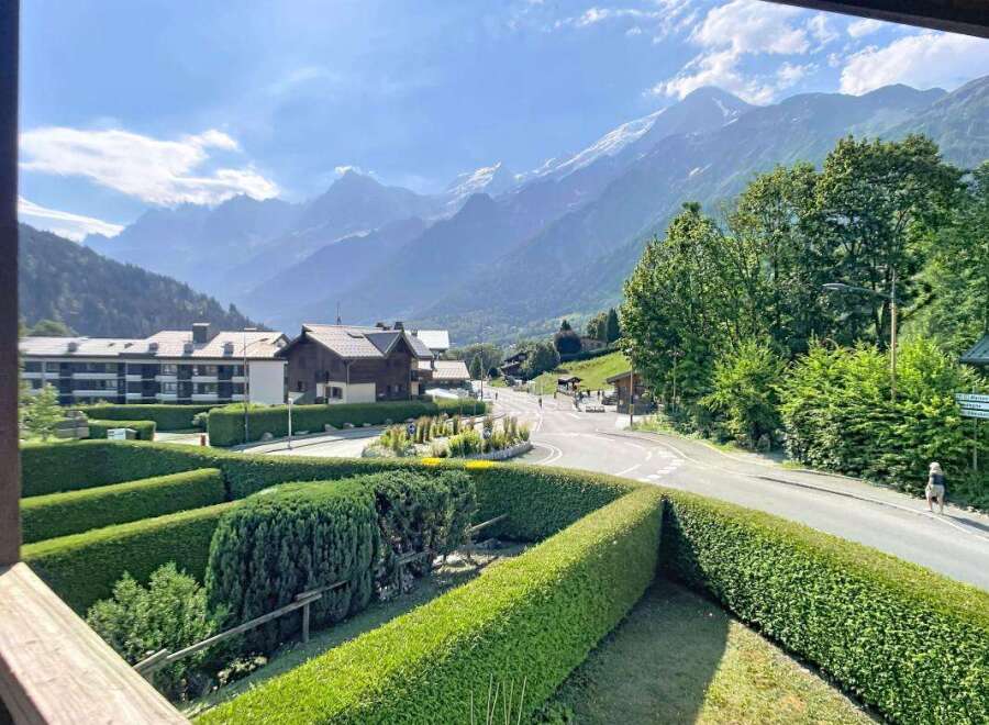 Experience breathtaking mountain views from this charming property, nestled amidst lush greenery and manicured hedges.