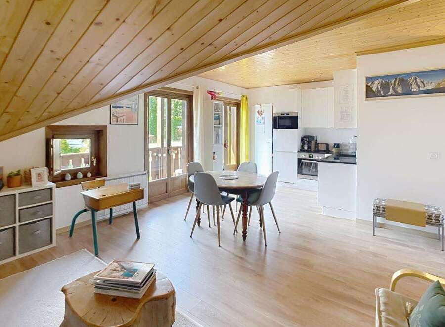 This charming open-plan living space features a modern white kitchen with ample counter space and integrated appliances, perfect for home chefs.