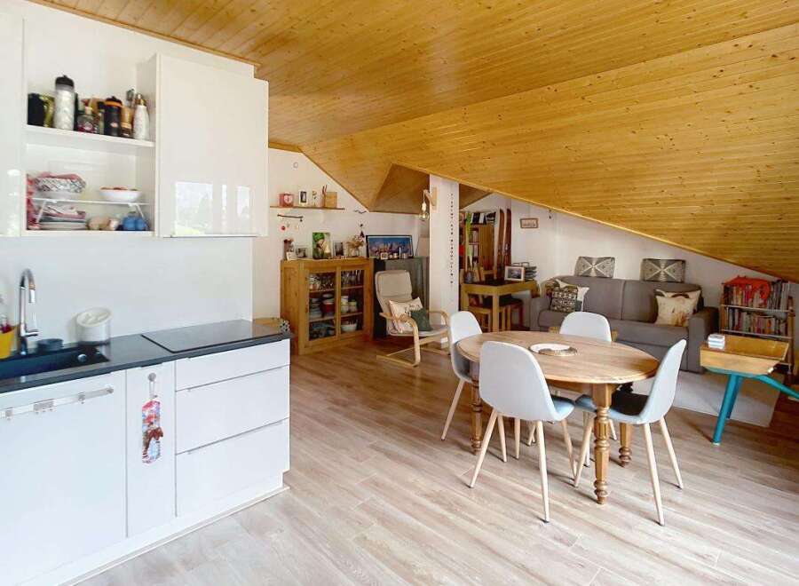 Discover this charming attic apartment featuring a modern white kitchen with ample storage and a sleek countertop.