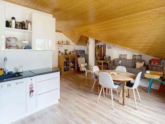 Discover this charming attic apartment featuring a modern white kitchen with ample storage and a sleek countertop.