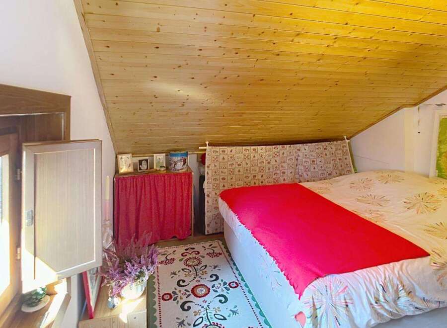 Experience cozy living in this charming attic bedroom, featuring a sloped wooden ceiling that adds warmth and character.