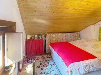 Experience cozy living in this charming attic bedroom, featuring a sloped wooden ceiling that adds warmth and character.