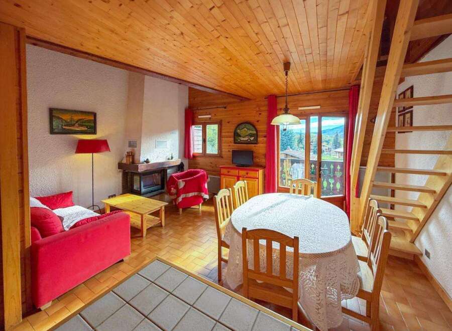 Experience cozy living in this charming mountain chalet, featuring a warm wood-paneled interior and a welcoming fireplace.