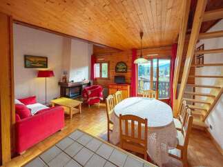 Experience cozy living in this charming mountain chalet, featuring a warm wood-paneled interior and a welcoming fireplace.