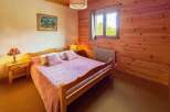 Experience cozy comfort in this charming bedroom, featuring a warm wooden interior and a comfortable bed adorned with pink linens.