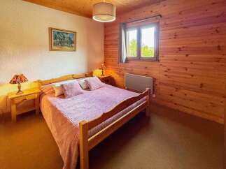 Experience cozy comfort in this charming bedroom, featuring a warm wooden interior and a comfortable bed adorned with pink linens.