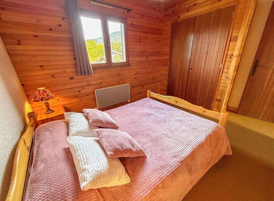 Experience cozy mountain living in this charming bedroom featuring warm wooden paneling throughout.