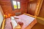 Experience cozy mountain living in this charming bedroom featuring warm wooden paneling throughout.