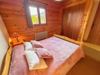 Experience cozy mountain living in this charming bedroom featuring warm wooden paneling throughout.