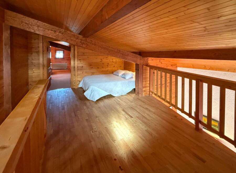 Experience rustic charm in this cozy loft bedroom, featuring a comfortable bed with crisp white linens.