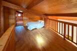 Experience rustic charm in this cozy loft bedroom, featuring a comfortable bed with crisp white linens.