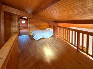 Experience rustic charm in this cozy loft bedroom, featuring a comfortable bed with crisp white linens.