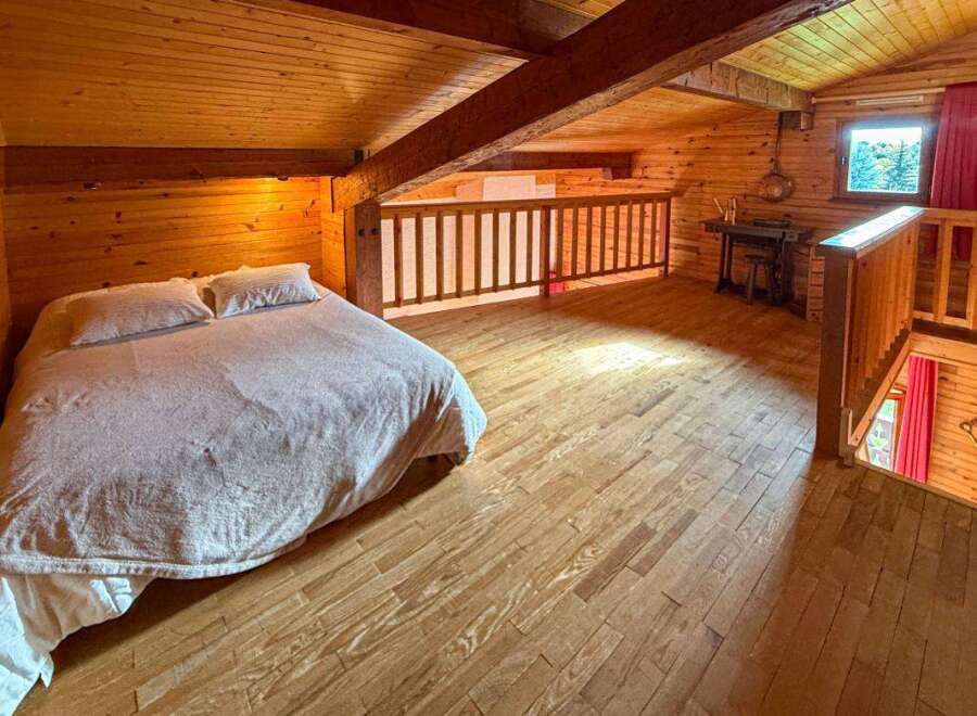 Experience rustic charm in this cozy loft bedroom, featuring a comfortable bed with plush pillows and a warm, wood-paneled ambiance.
