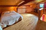 Experience rustic charm in this cozy loft bedroom, featuring a comfortable bed with plush pillows and a warm, wood-paneled ambiance.